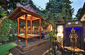 A traditional wooden structure with a tiled roof, possibly a gazebo, surrounded by lush greenery and a pool area. - Jerogadung House (Ubud)
