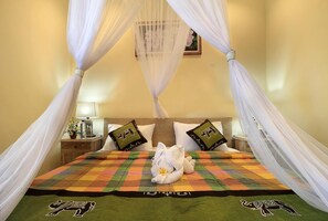 A bed with a canopy, pillows with elephant designs, and a towel on the bed. - Jerogadung House (Ubud)