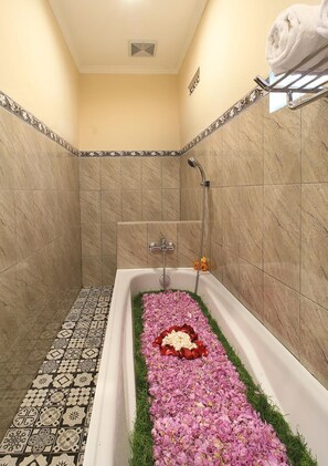 A bathroom with a bathtub, shower, and decorative tiles. - Jerogadung House (Ubud)