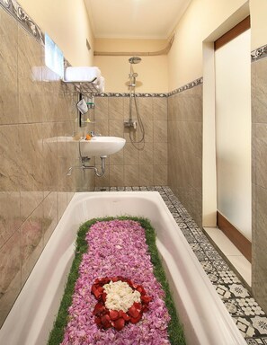 A bathroom with a bathtub filled with rose petals and a shower area. - Jerogadung House (Ubud)