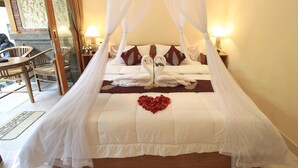 Una cama con dosel, ropa de cama blanca y almohadones decorativos.