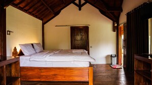 Ein Schlafzimmer mit Holzbett, Holztür und einem kleinen Wäschekorb.