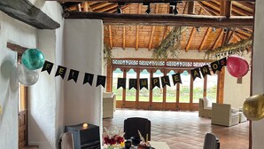 A dining area with a table set for a meal, chairs, a decorative banner, and a view of the outdoors. - Hacienda La Armenia - Cottage Hotel (Sopó)