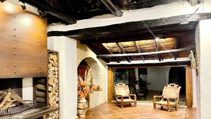 A rustic interior with a fireplace, wooden chairs, and a stone floor. - Hacienda La Armenia - Cottage Hotel (Sopó)