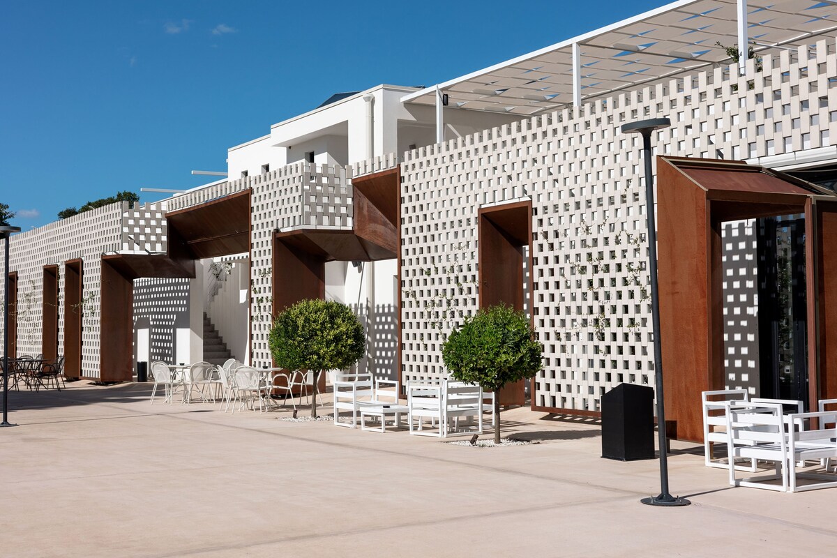 A modern building with a white facade, multiple balconies, and outdoor seating areas.