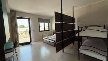 A room with a bunk bed, a desk with a chair, a radiator, and a window with a view of the outside.