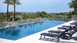 A swimming pool with lounge chairs and a view of the landscape. - Tenuta San Marco (Noto)