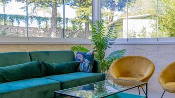 A modern living room with a green sofa, a yellow armchair, and a glass coffee table.