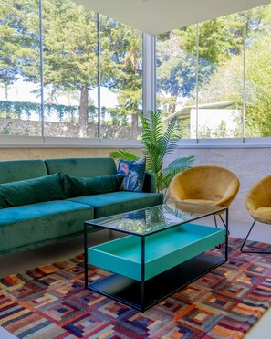 A modern living room with a green sofa, a yellow armchair, and a glass coffee table. - Tenuta San Marco (Noto)