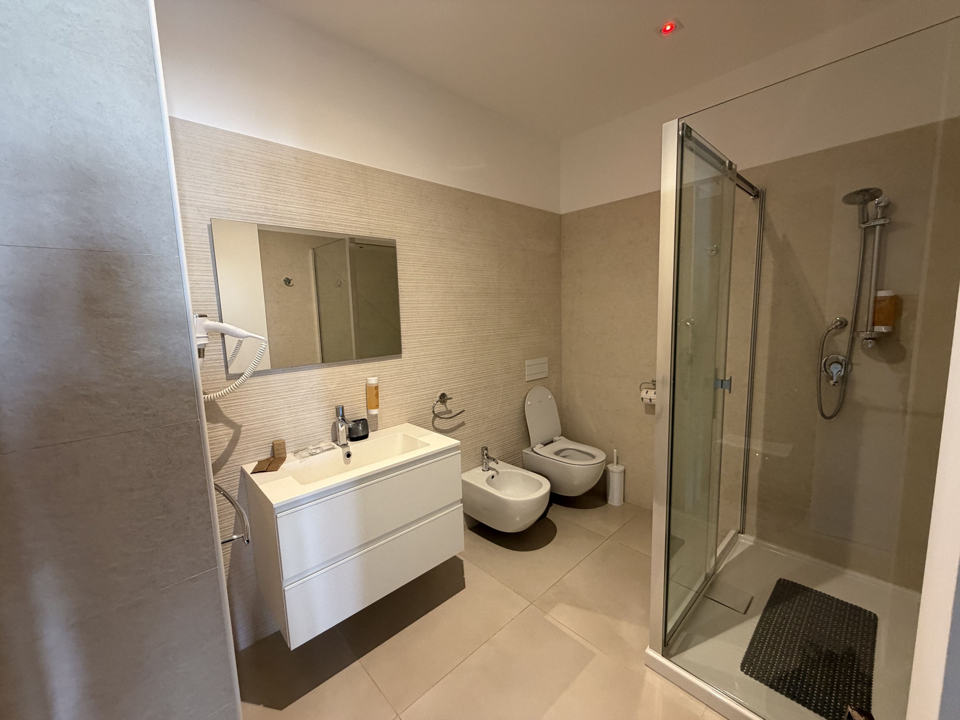 A modern bathroom with a glass-enclosed shower, a white sink, and a toilet.