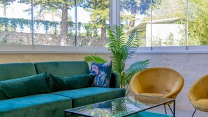 Ein stilvolles Wohnzimmer mit einem grünen Sofa, einem gelben Sessel und einem Glastisch.