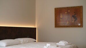 Ein Hotelzimmer mit einem Bett, Kissen, einem ordentlich gefalteten Handtuch und einem Bild an der Wand.