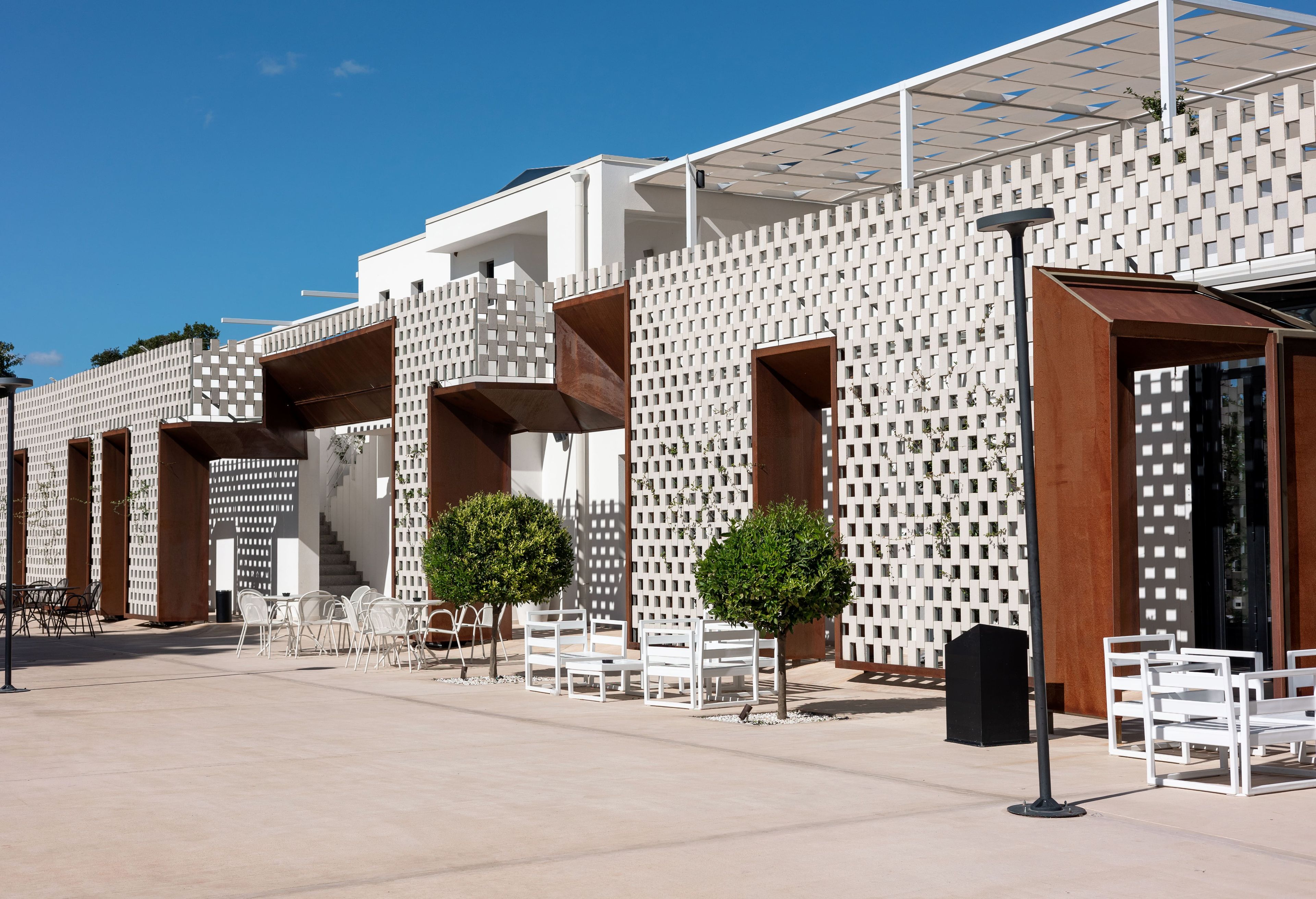Un bâtiment moderne à la façade blanche, doté de nombreux balcons et d’espaces de détente en plein air.