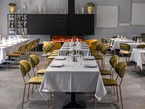 Un restaurante con mesas dispuestas para comer, sillas y una chimenea al fondo.