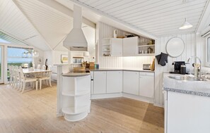 Une cuisine moderne avec des meubles blancs, un îlot central et un coin repas offrant une vue agréable.