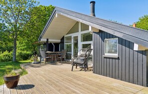 A wooden deck with outdoor furniture, a covered patio area, and a large window. - 3 bedroom stunning home in Martofte (Martofte)
