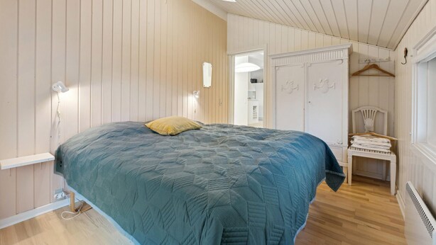 Een slaapkamer met een bed, nachtkastje, kledingkast en een hangstoel.