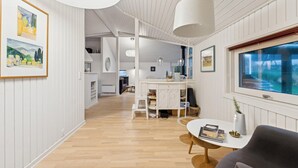 Een modern interieur met een houten vloer, witte muren en een eethoek met een ronde tafel en stoelen.