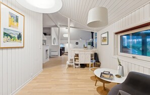 A modern interior with a wooden floor, white walls, and a dining area with a round table and chairs. - 3 bedroom stunning home in Martofte (Martofte)