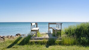 Een houten terras met twee banken met uitzicht op een rustige zee.