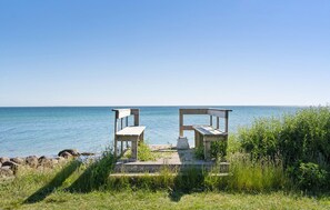 A wooden deck with two benches overlooking a calm sea. - 3 bedroom stunning home in Martofte (Martofte)