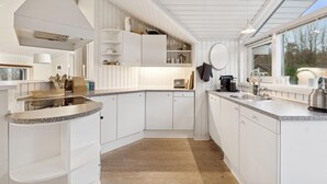 Een moderne keuken met witte kastjes, granieten werkbladen en een groot raam voor natuurlijk licht.