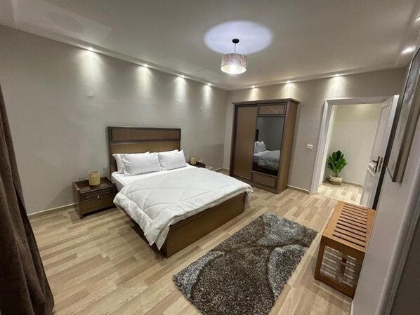 A bedroom with a bed, bedside table, and a mirror. - Skyline Luxury Suites 5 Mins From Cairo Airport (Cairo)
