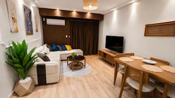 Una sala de estar moderna con sofá, mesa de centro, televisor y comedor.