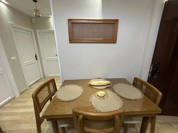 A dining area with a wooden table, four woven placemats, and two chairs. - Skyline Luxury Suites 5 Mins From Cairo Airport (Cairo)