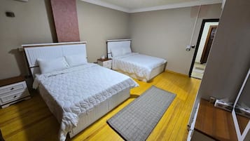 Un dormitorio con dos camas, suelo de madera y alfombra gris.