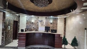 Zona de recepción con pared de mármol, mostrador de recepción, candelabro y un pequeño árbol de Navidad.