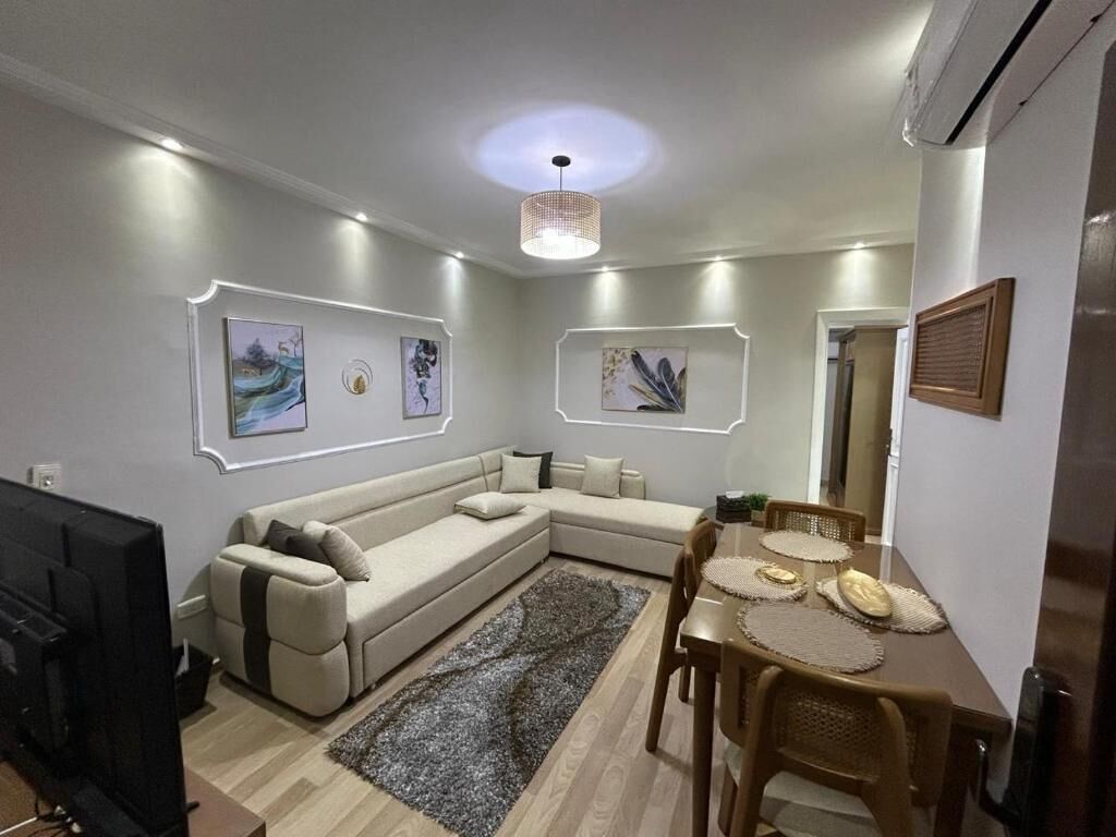 Una sala moderna con un sofá modular, una mesa de comedor con sillas y obras de arte en las paredes.