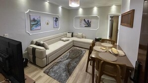 Una sala moderna con un sofá modular, una mesa de comedor con sillas y obras de arte en las paredes.