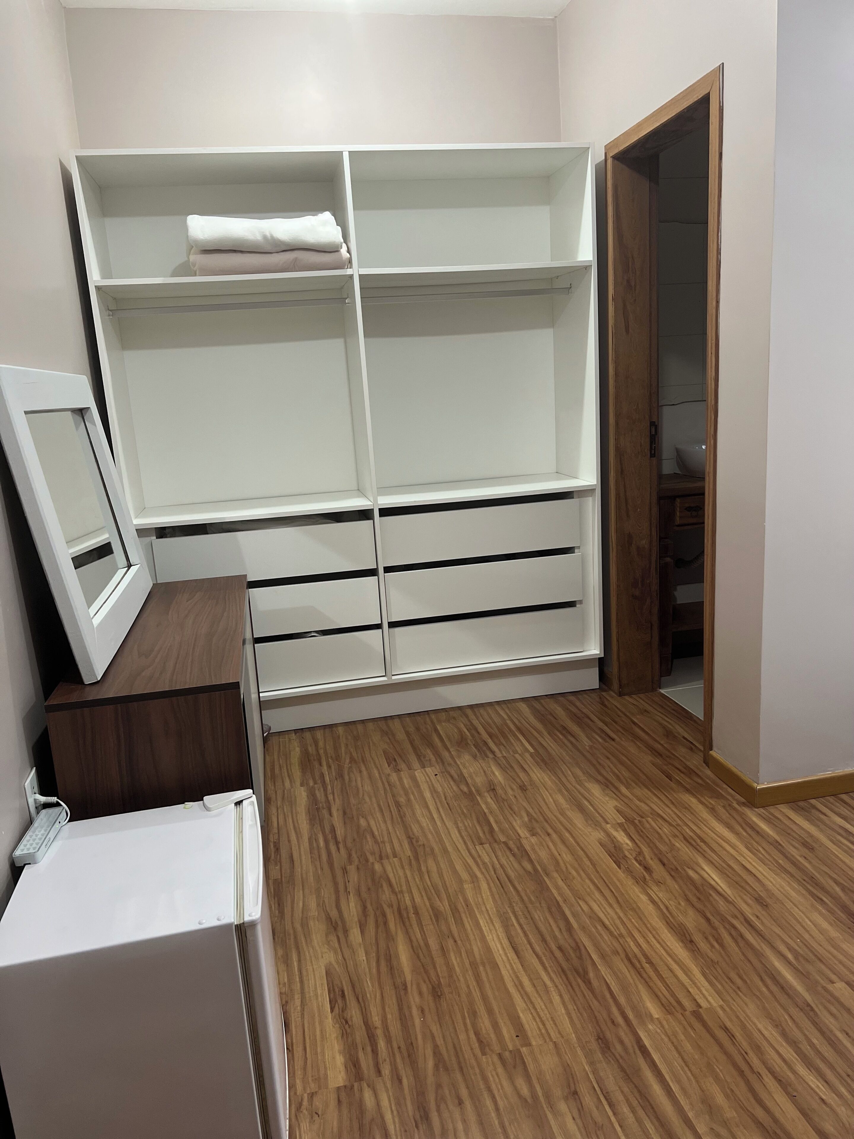Um quarto com uma cama, um guarda-roupa e uma escrivaninha com telefone.