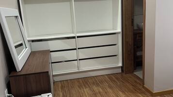 Um quarto com uma cama, um guarda-roupa e uma escrivaninha com telefone.