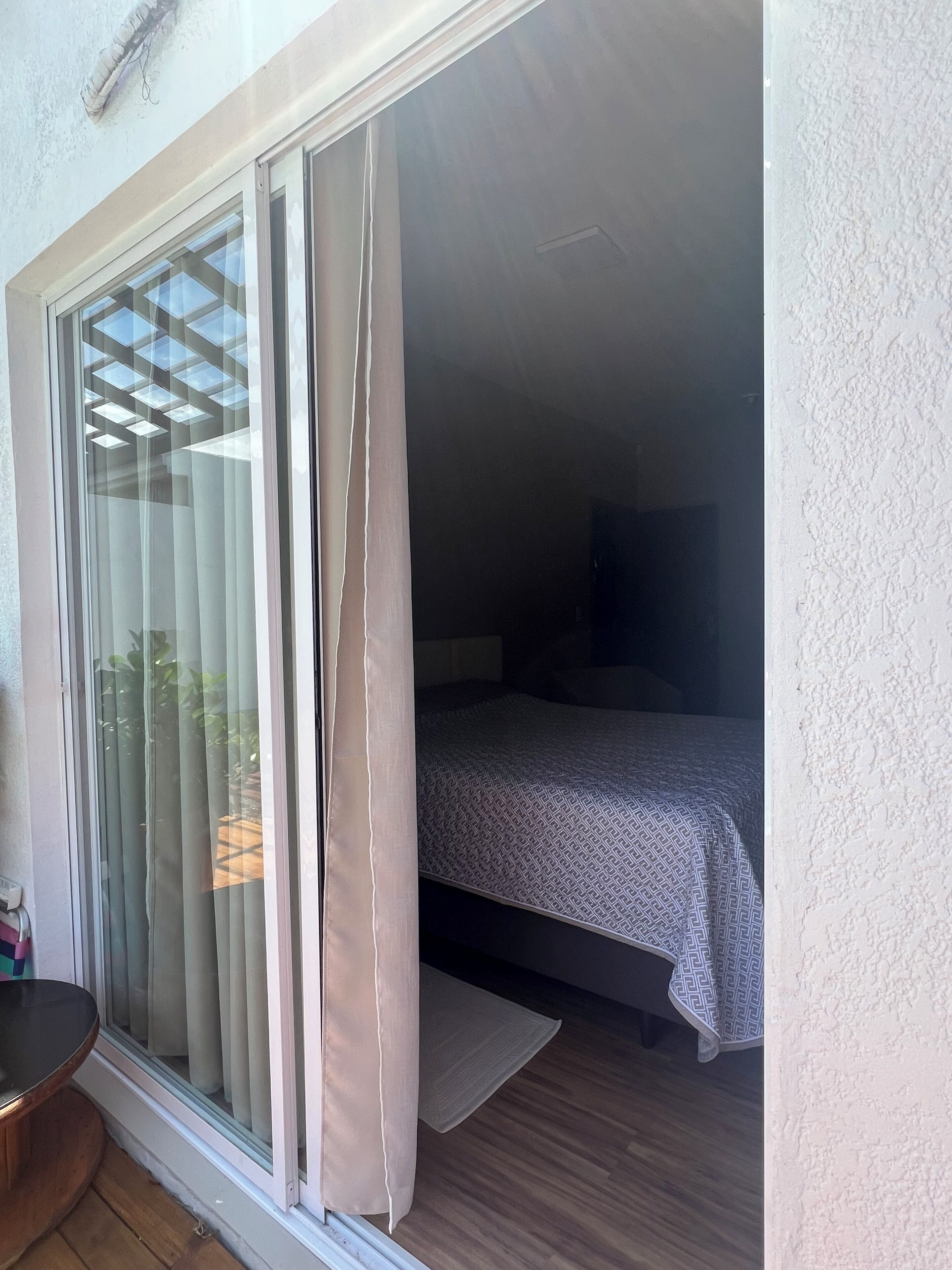 Um quarto com uma cama, uma janela com cortinas e piso de madeira.