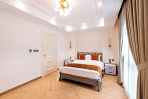 Ein Hotelzimmer mit Bett, Nachttischen, einer Kandelaberleuchte und Vorhängen.