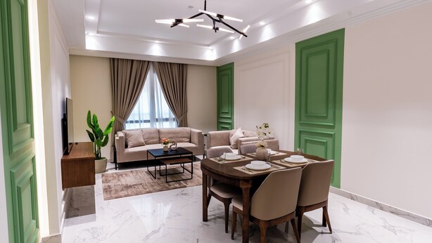 Una sala moderna con un sofá, una mesa de comedor con sillas, una mesa de centro, un televisor y una planta.