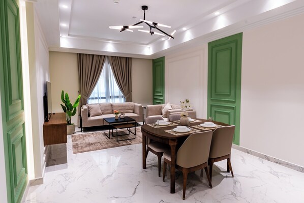 Un salon moderne comprenant un canapé, une table à manger avec des chaises, une table basse, un téléviseur et une plante.