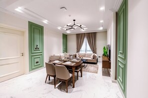 A modern living room with a dining area, green doors, and a chandelier.