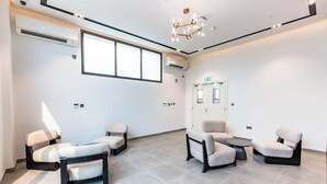 A modern waiting area with four chairs, a small table, and a chandelier. - Artan Residence & Suites (Doha)
