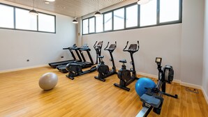 A gym with exercise equipment, a large exercise ball, and large windows. - Artan Residence & Suites (Doha)