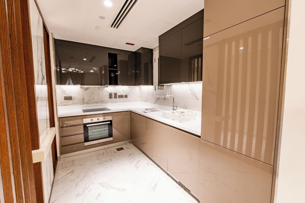 A modern kitchen with marble countertops, a built-in oven, and a large mirror.
