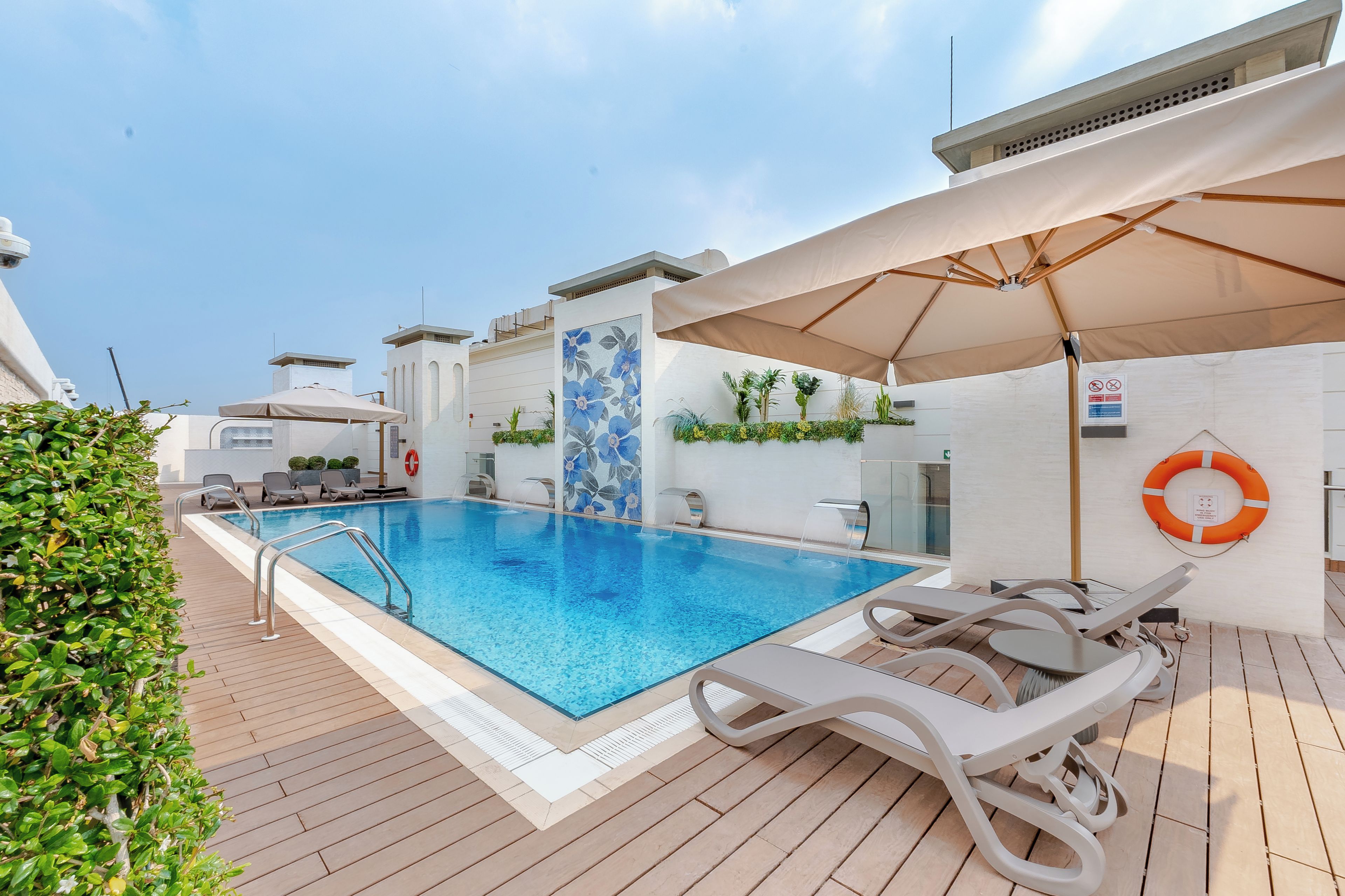 Uma área de piscina no terraço, com piscina azul cristalina, espreguiçadeiras e guarda-sóis.