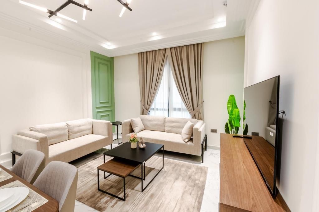 Uma sala de estar moderna com sofás, uma mesa de centro, uma televisão e uma grande janela com cortinas.