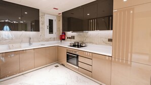 Una cocina moderna con encimera de mármol, horno empotrado y muebles oscuros.