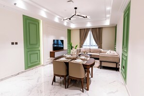 Una sala moderna con comedor, puertas verdes, televisor de pantalla plana y un conjunto de sofás.