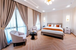 Habitació d'hotel amb un llit, una cadira, una taula petita i una petita taula de nit.