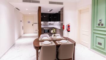 Un comedor con una mesa dispuesta para cuatro, una cocina al fondo y un extintor de incendios en la pared.