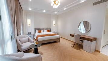 Quarto de hotel com cama, escrivaninha, cadeira, espelho redondo e luminária no teto.